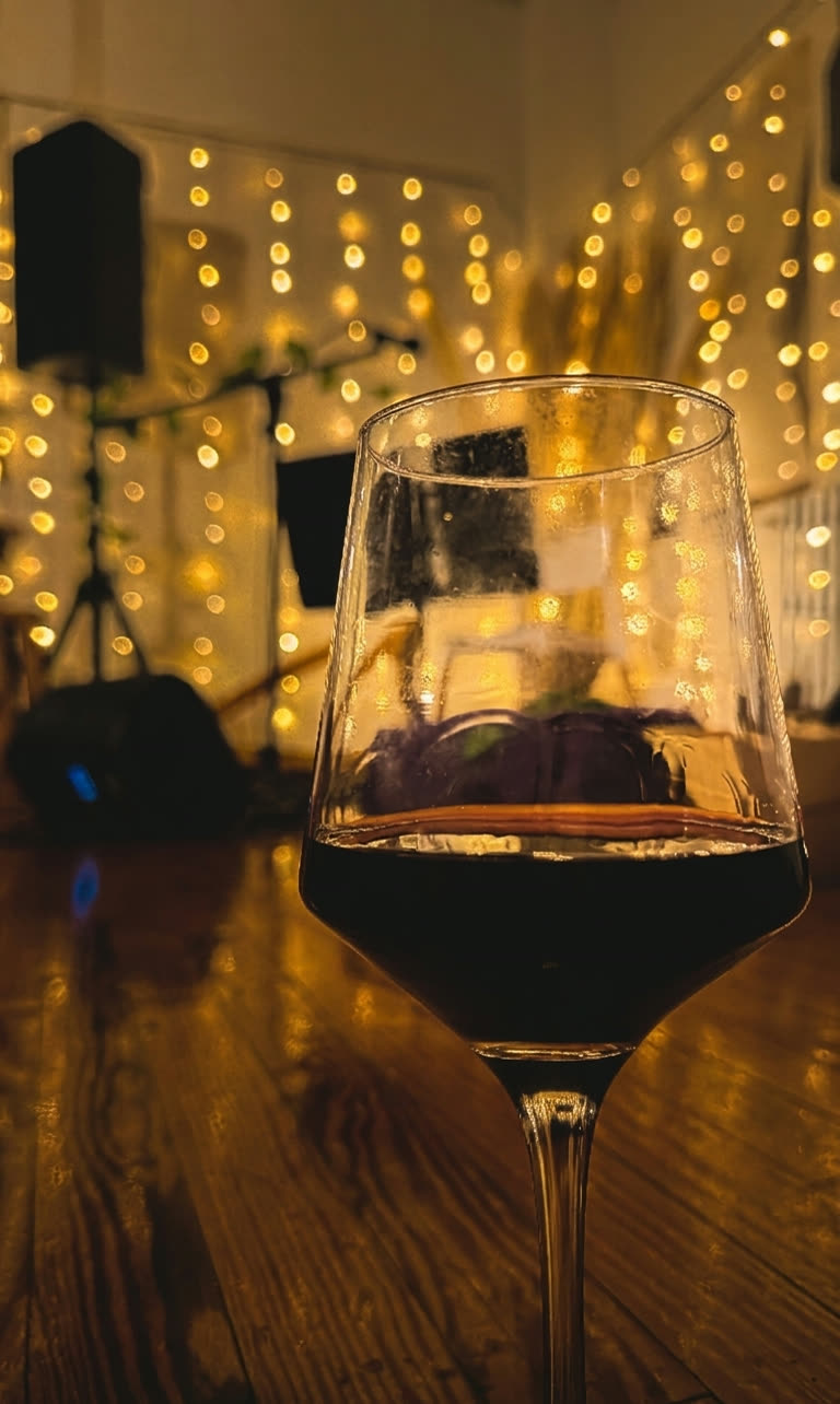 Copa de vino tinto junto a una guirnalda de luces cálidas