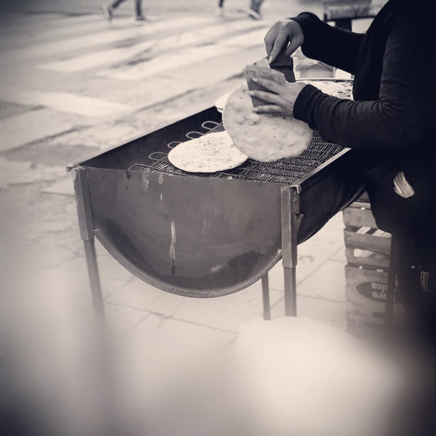 Manos amasando sobre un carrito de comida callejera, blanco y negro