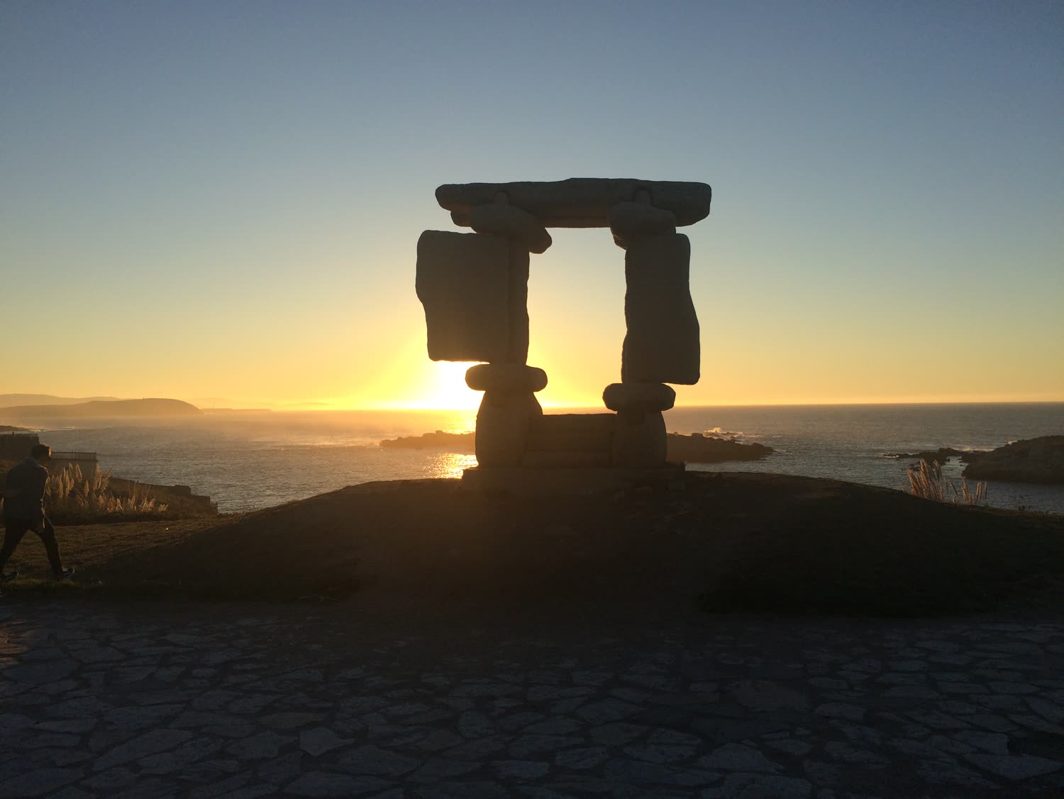 Estructura de piedra en silueta contra un cielo de atardecer