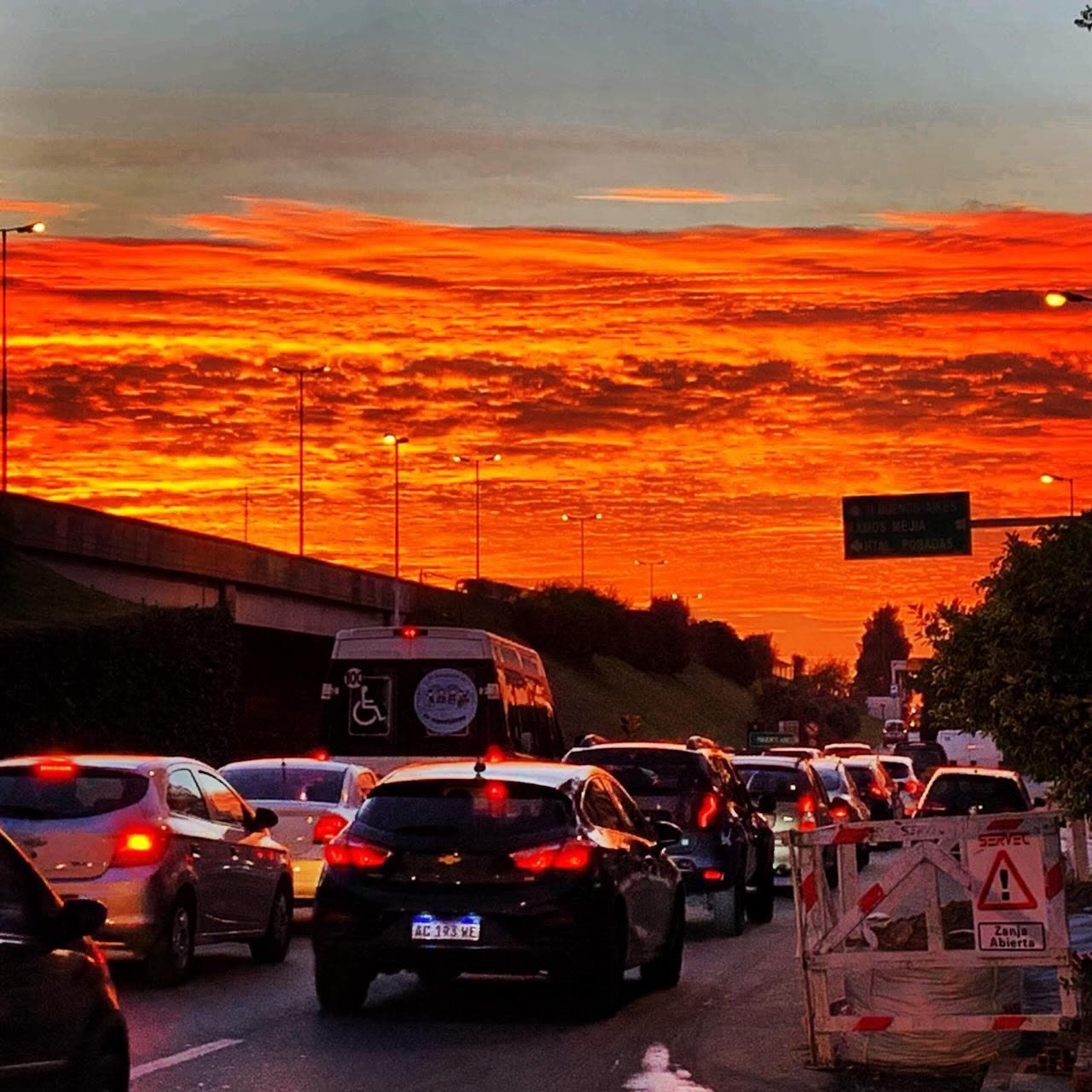 Tráfico detenido bajo un cielo naranja de atardecer