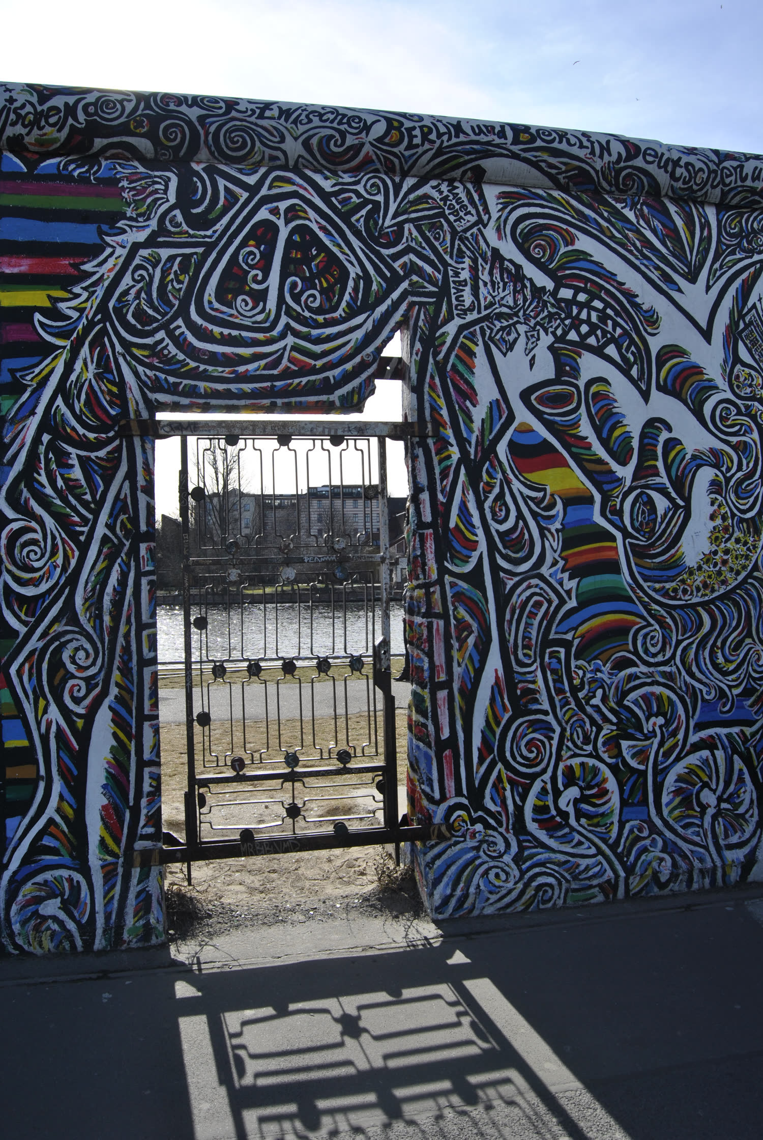 Portón enrejado con mural colorido en un tramo del Muro de Berlín