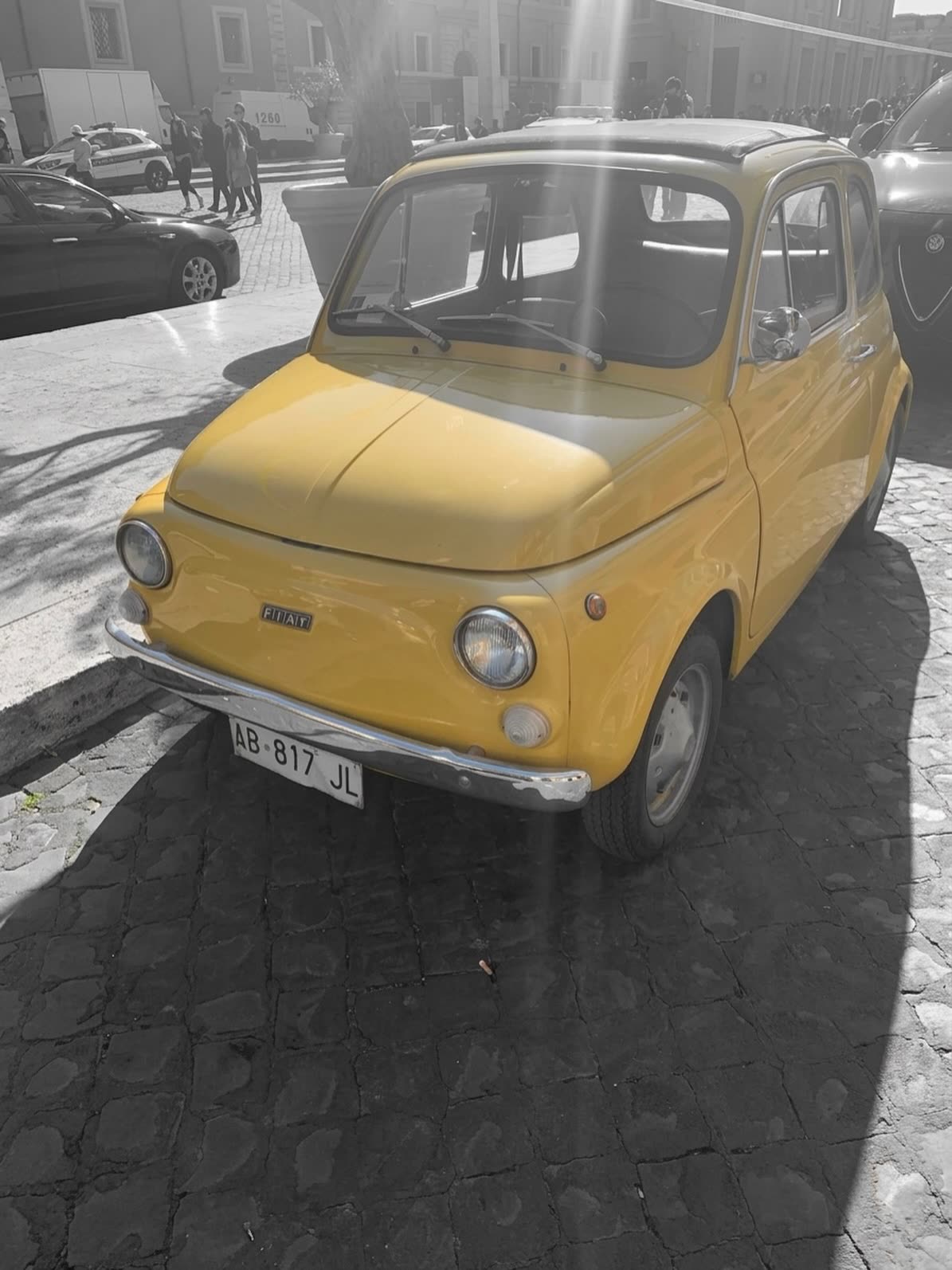Auto Fiat 500 amarillo estacionado en la calle, blanco y negro