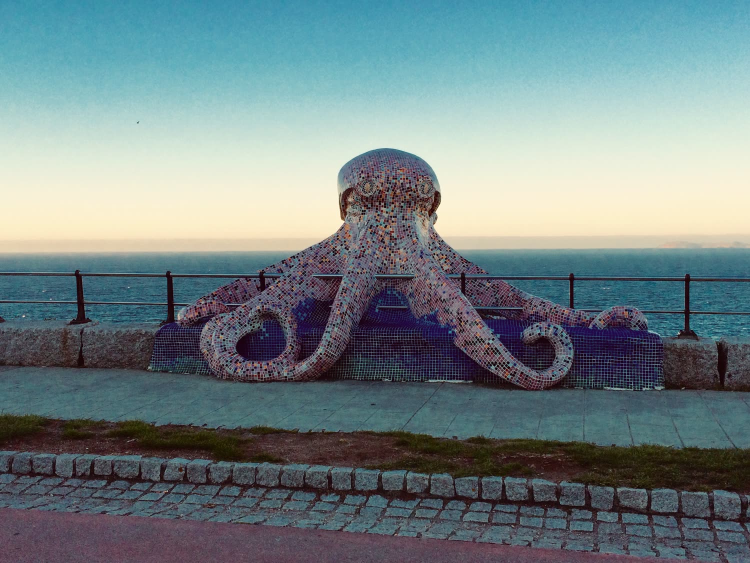 Escultura de pulpo revestida en mosaico frente al mar, al amanecer