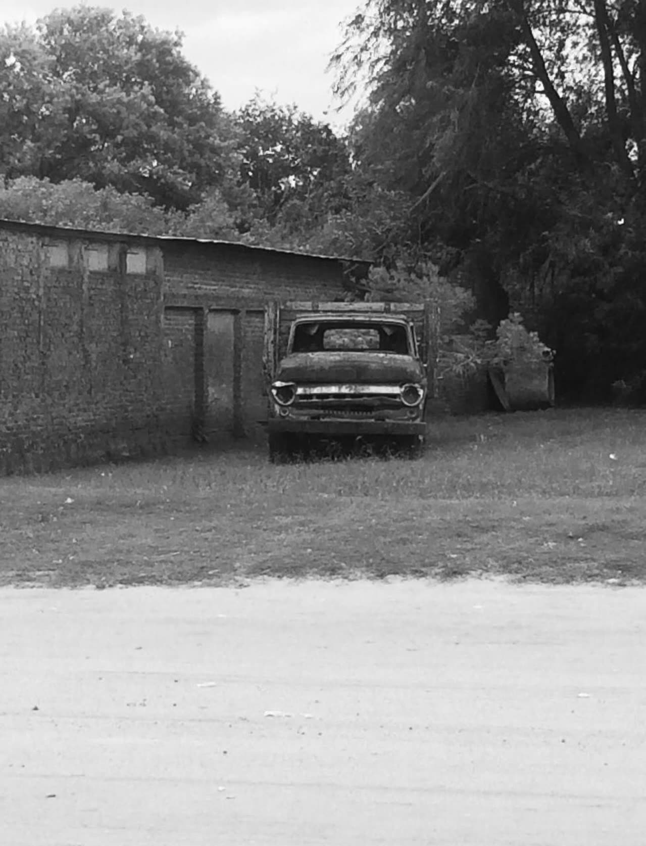Camión antiguo abandonado en un descampado, blanco y negro